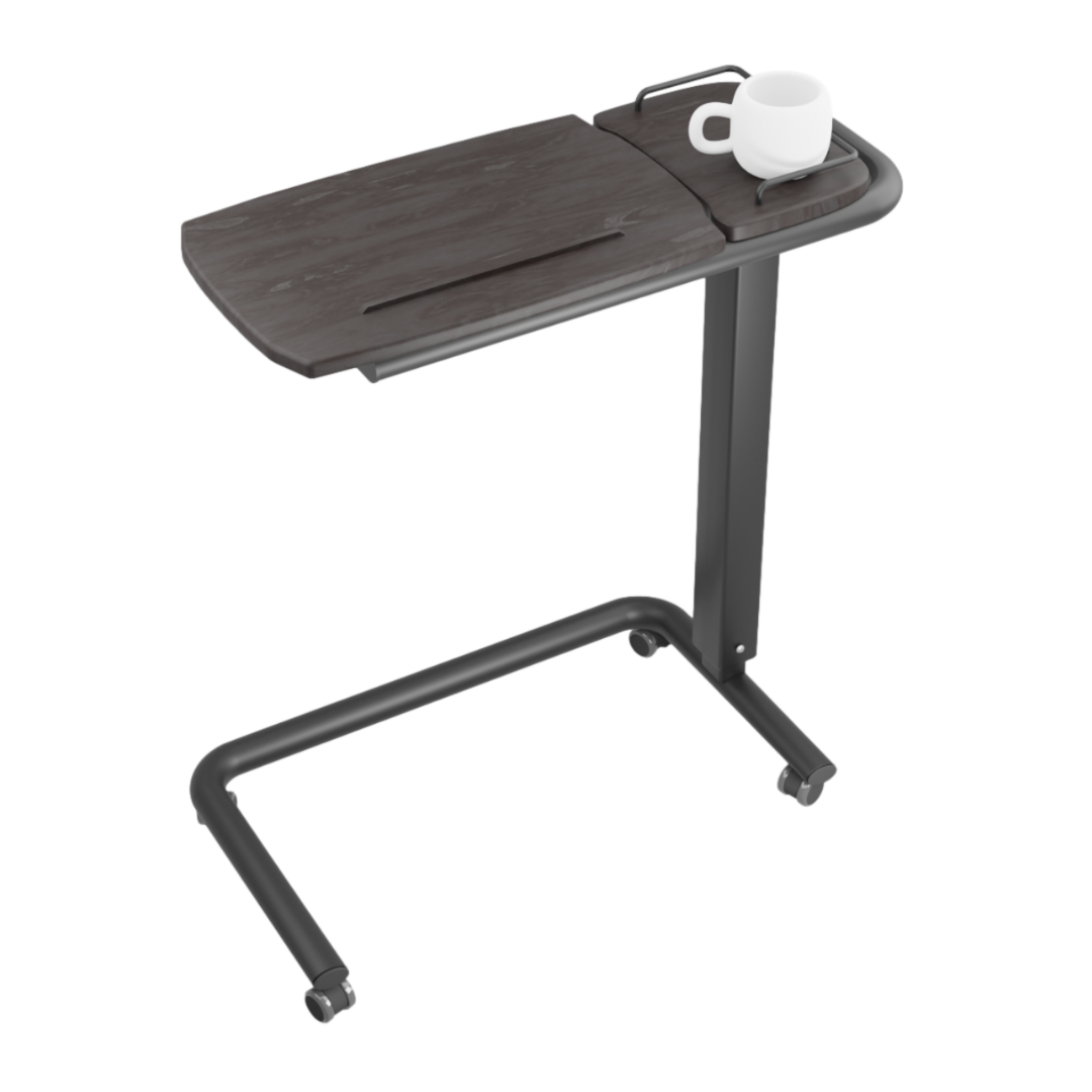 The iCare Medical Over Bed Tilting Table features a dark wood surface with a raised edge, metal frame, height adjustment, four wheels for easy movement, and a multi-purpose design—ideal for any room. A white mug sits in one corner.